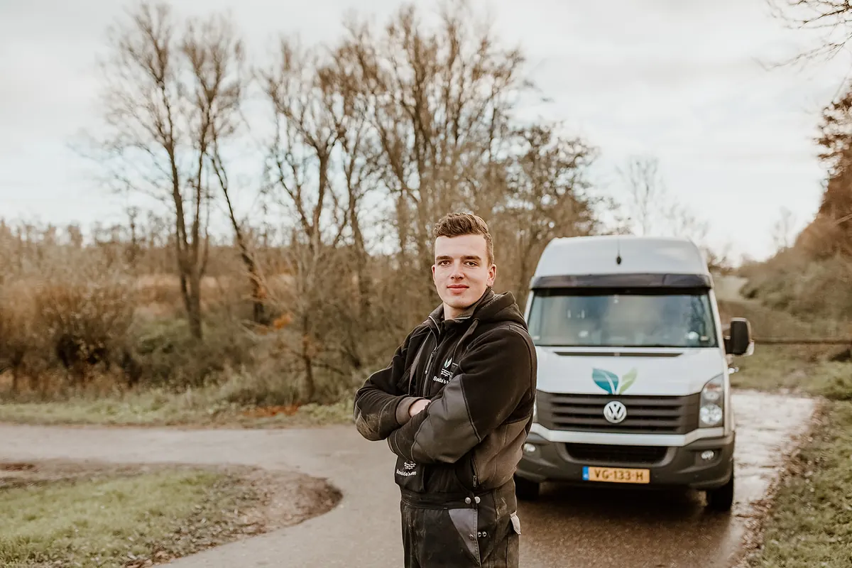 Pieter Dekker, hovenier bij Buwalda's tuinen, met de armen over elkaar voor de bus