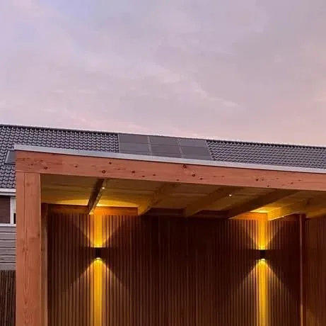 Buitenverblijf met verticale houten latten en warm licht van wandlampen in de schemering